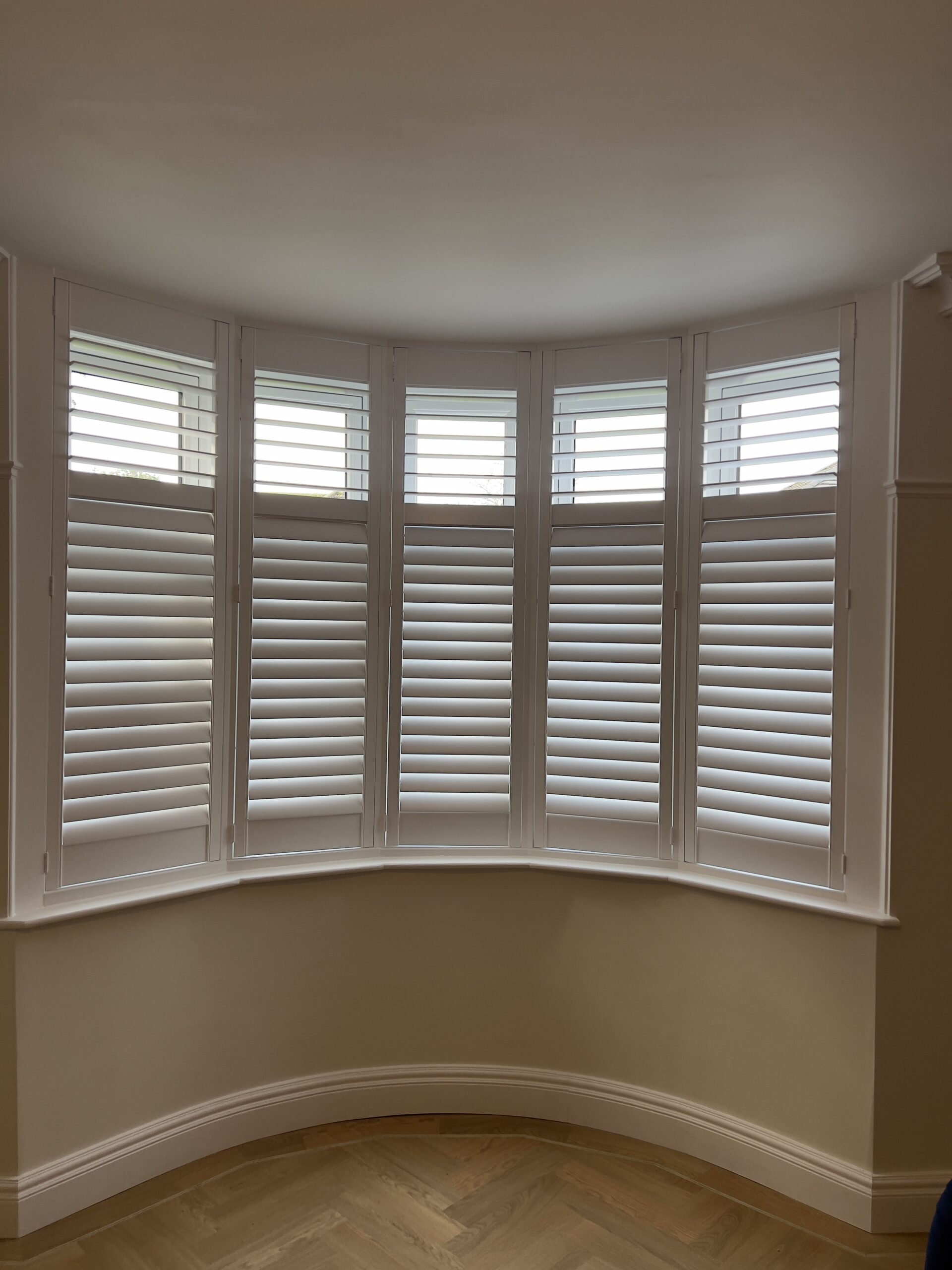 A bay window covered by white, full height shutters